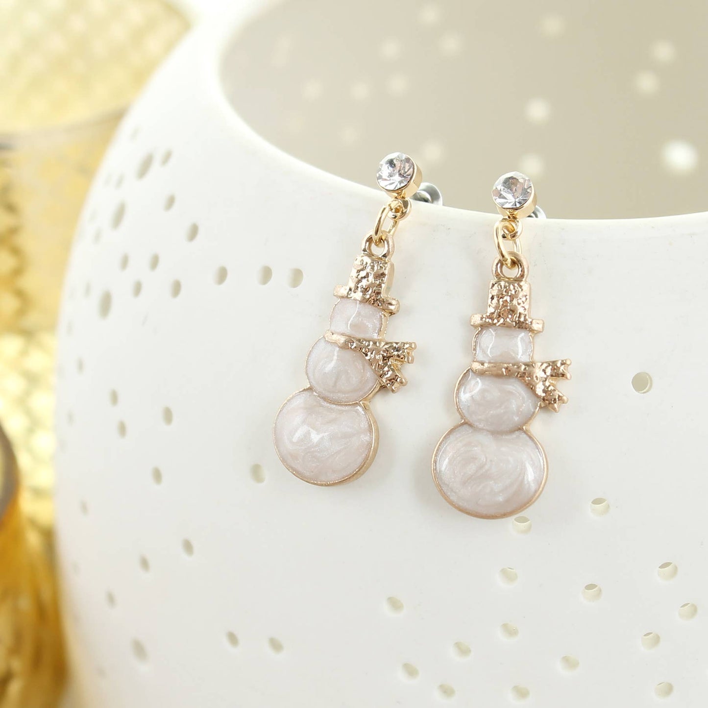 Gold and enamel snowman Christmas earrings with crystal post detail, displayed on a white textured background.