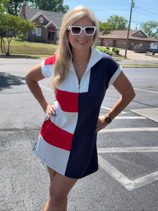 Woman in a red, white, and blue dress standing on a street.
