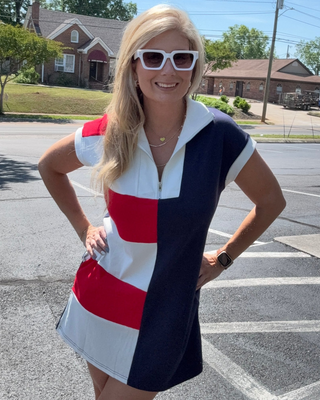 Woman wearing a red, white, and blue dress with sunglasses on a street.