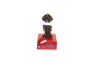 Dachshund ornament holding a bone, standing on a red base with 'My Best Buddy' text.