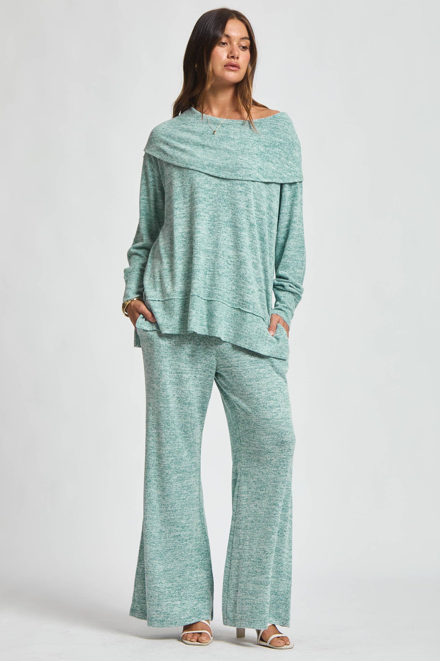 Woman wearing a teal cashmere hacci two-piece set with a draped neckline top and wide-leg pants.