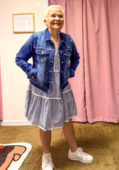 Senior model wearing striped dress and denim jacket in boutique dressing area