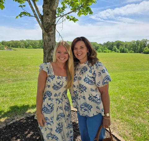 Two women smiling in coordinating blue floral outfits from The Pink Doxie Boutique