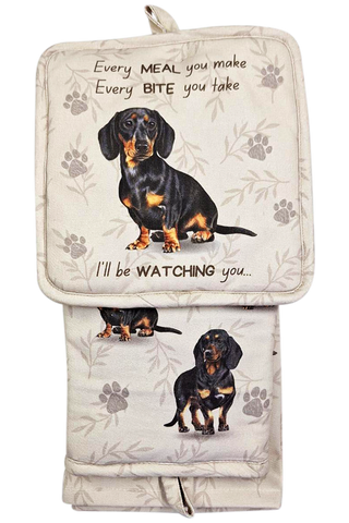 A 100% cotton oven mitt set with a black Dachshund design, including a mitt, pot holder, and kitchen towel.