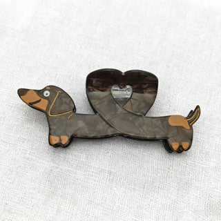 A dachshund-shaped hair clip with a heart design, featuring a geometric pattern and brown-and-tan coloring.