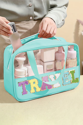Mint green clear PVC makeup bag with chenille TRAVEL lettering and top handles, filled with beauty products, from The Pink Doxie Boutique.
