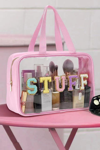 Pink clear PVC makeup bag with glitter chenille STUFF lettering and top handles, filled with beauty products, from The Pink Doxie Boutique.