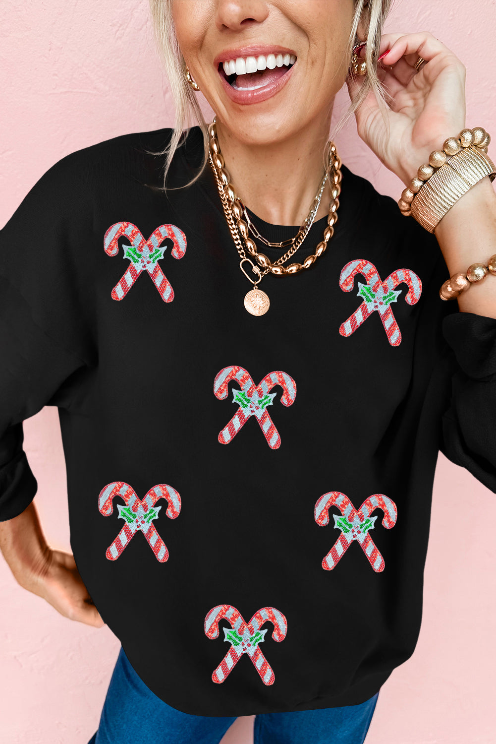 Woman wearing a black sweatshirt with festive candy cane patches — cozy Christmas pullover from The Pink Doxie Boutique