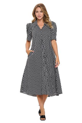 A woman wearing a midi-length A-line dress in a black-and-white geometric print with a notched collar, short bubble sleeves, and side pockets.