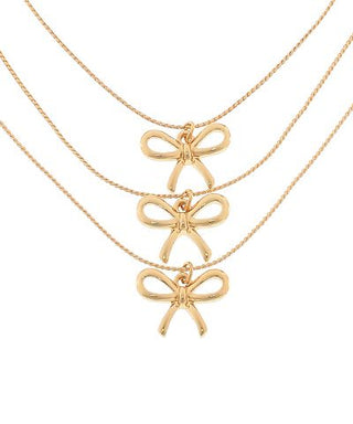 Gold bow pendant necklace with delicate layered chains, photographed for The Pink Doxie Boutique.