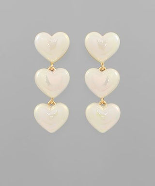 Cream acrylic heart drop earrings featuring three glossy hearts in a cascading design on a neutral background from The Pink Doxie Boutique.