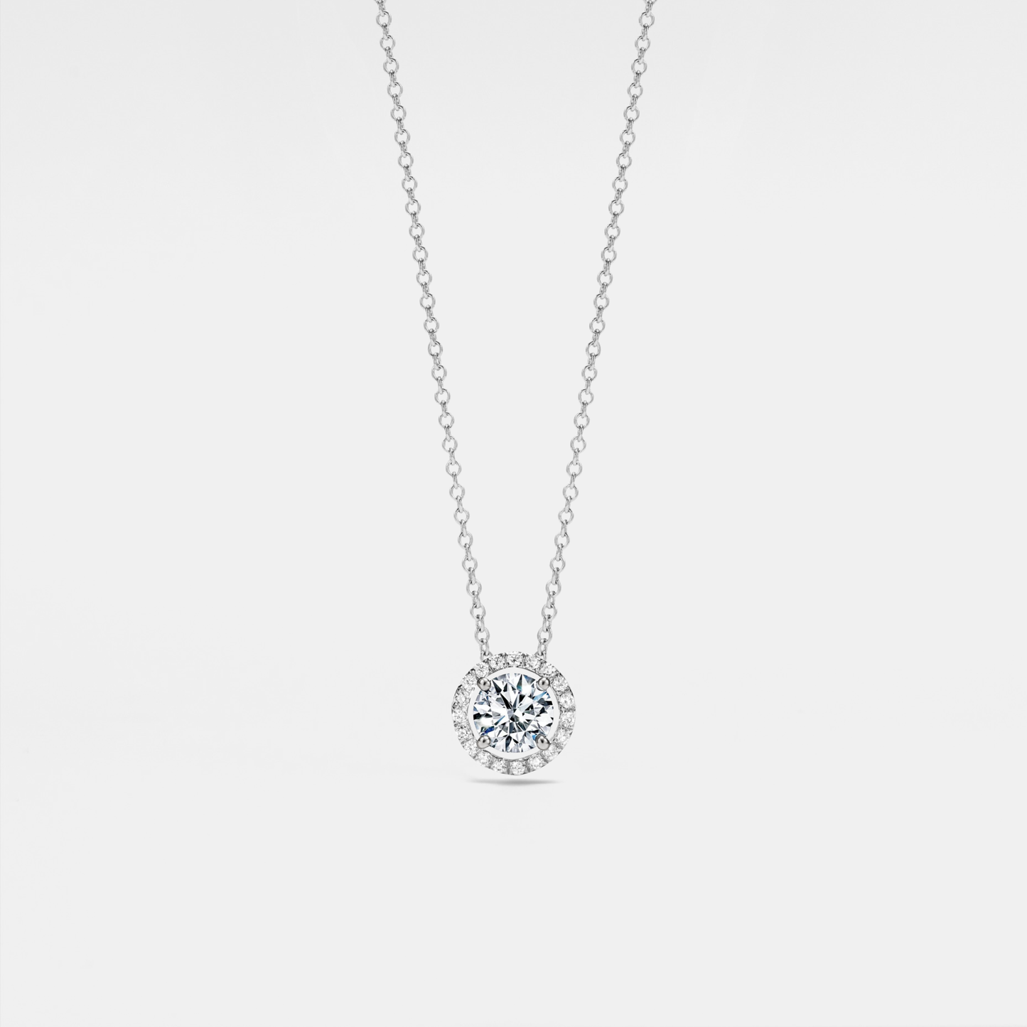 Four-prong moissanite halo pendant necklace in sterling silver with platinum plating — round D-color VVS1 stone sparkling on a delicate chain.