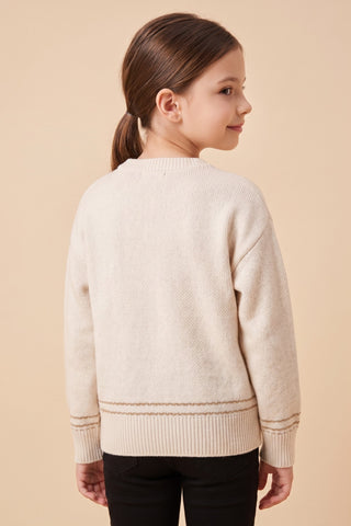 A girl wearing a cream fine gauge knit crew neck pullover sweater with a textured black and tan dachshund appliqué on the front and ribbed cuffs and hem.