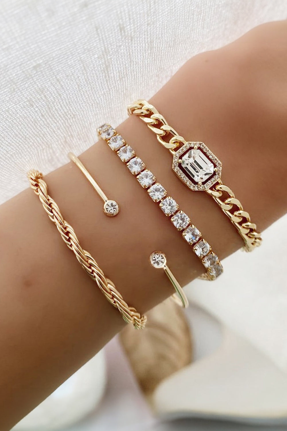 Set of four gold diamond-accented bangles including braided, chained, and rhinestone designs — elegant jewelry stack from The Pink Doxie Boutique.