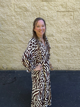 Woman wearing a maxi dress with mixed zebra and leopard prints, featuring a tie waist and balloon sleeves.