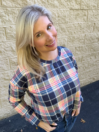 Woman wearing a plaid pullover top with a bubble hem, featuring shades of blue and yellow.