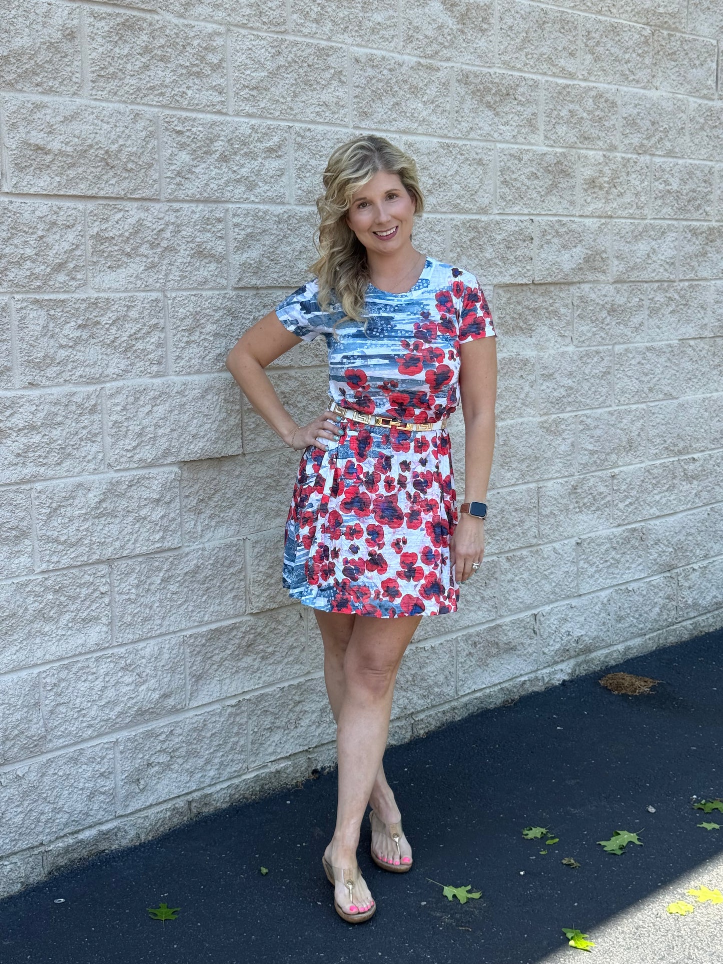 Woman wearing a floral dress standing against a stone wall.
