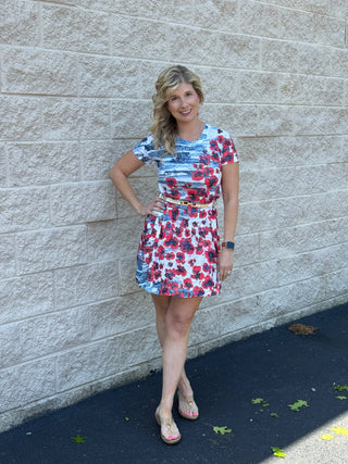 Woman wearing a floral dress standing against a stone wall.
