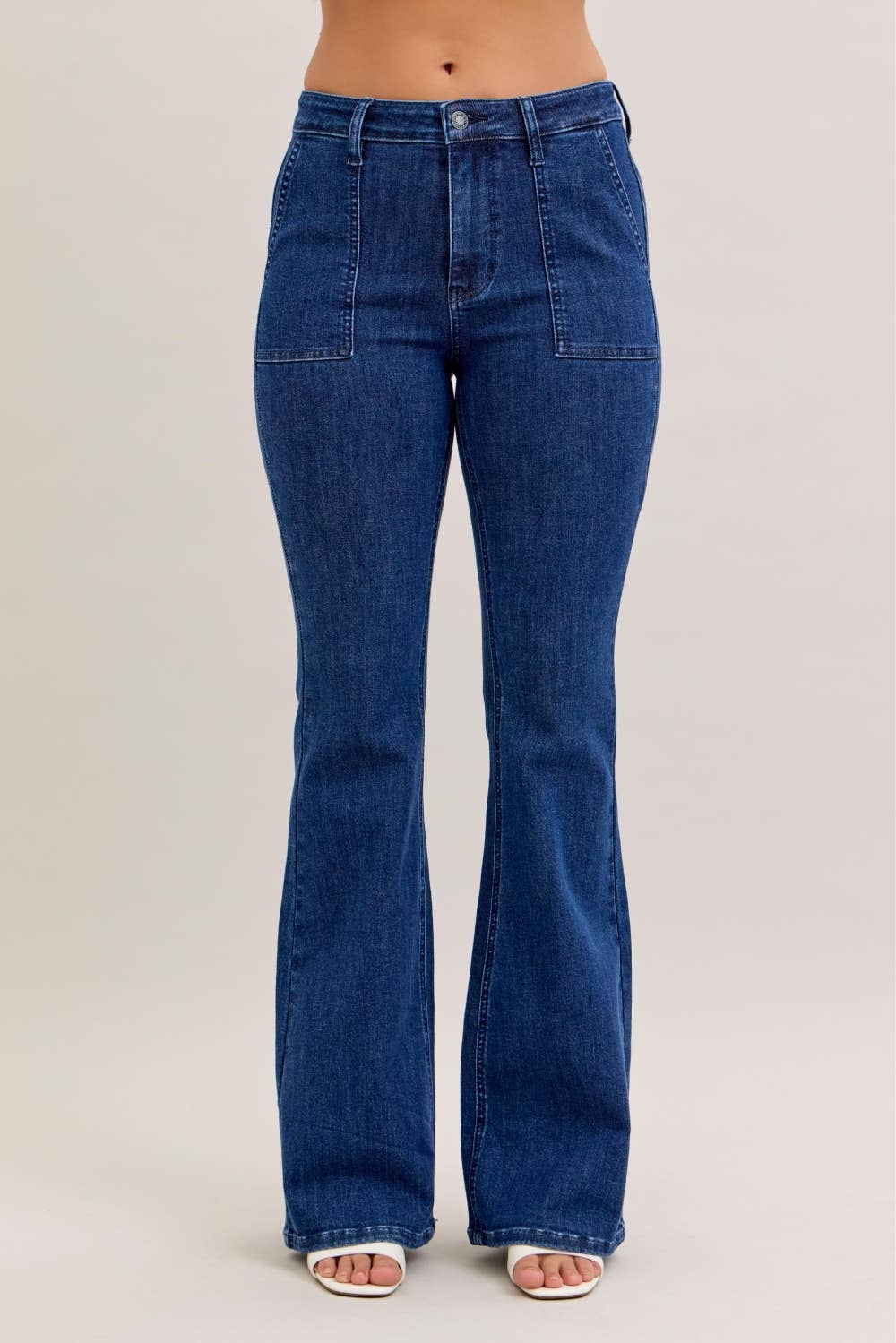 Model wearing dark wash high waisted Judy Blue flare jeans with front patch pockets, standing against a neutral background.