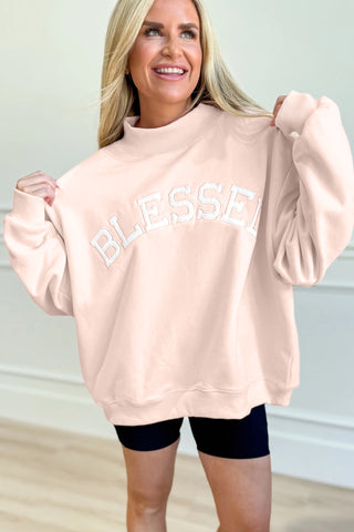 Woman wearing light pink oversized Blessed sweatshirt with mock neck and embroidered Blessed graphic from The Pink Doxie Boutique.