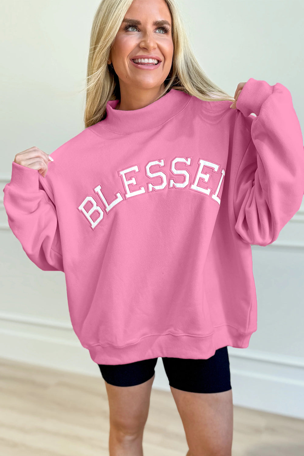 Woman wearing bright pink oversized Blessed sweatshirt with embroidered lettering from The Pink Doxie Boutique.
