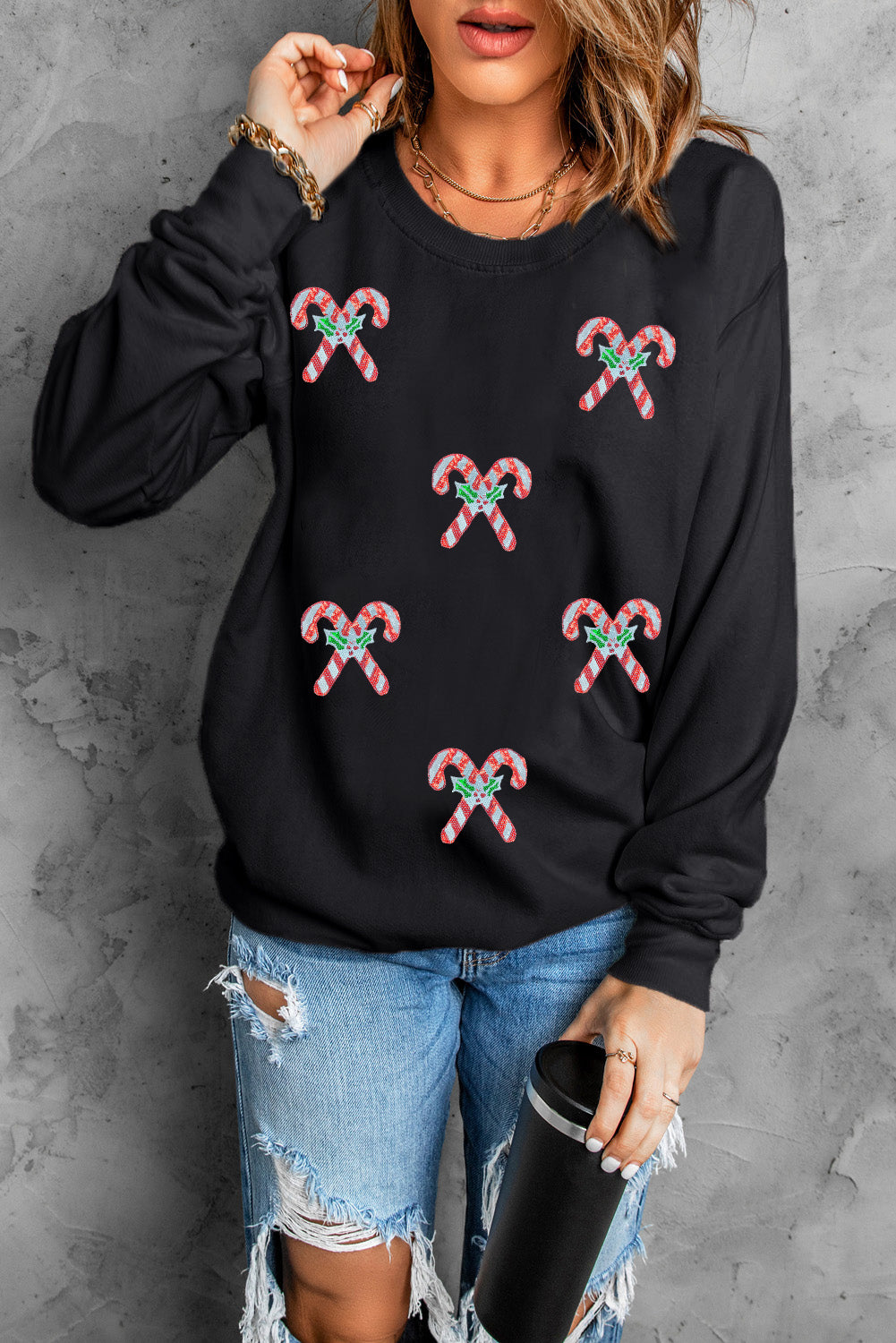 Woman wearing a black sweatshirt with festive candy cane patches — cozy Christmas pullover from The Pink Doxie Boutique