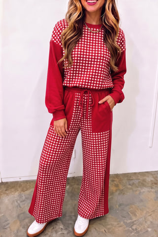 A woman wearing a two-piece matching set with a red and white gingham patchwork pullover with solid red sleeves and coordinating wide-leg pants with a drawstring waist and side pockets.