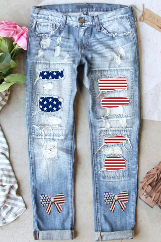 Light blue distressed straight-leg jeans with stars, stripes, and bow patches, patriotic Americana denim from The Pink Doxie Boutique.