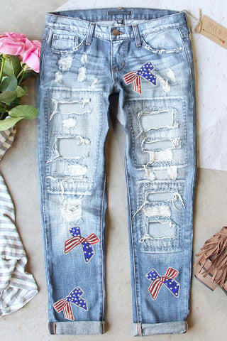 Light blue distressed straight-leg jeans with patriotic red, white, and blue sequin bow patches from The Pink Doxie Americana Collection.