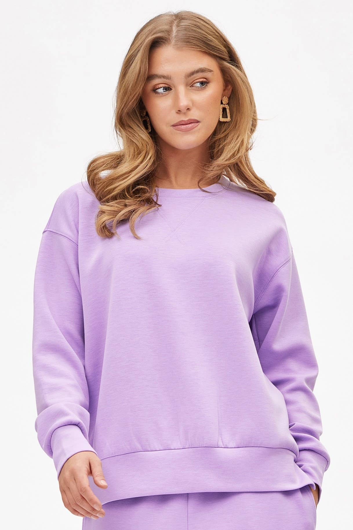 Woman wearing lilac crew neck pullover and matching joggers from The Pink Doxie Travel Collection — wrinkle-free and chic travel outfit.