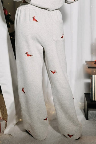 Heather gray wide-leg sweatpants with a high waist, adjustable drawstring, and allover embroidered dachshunds wearing Santa hats in red and brown.