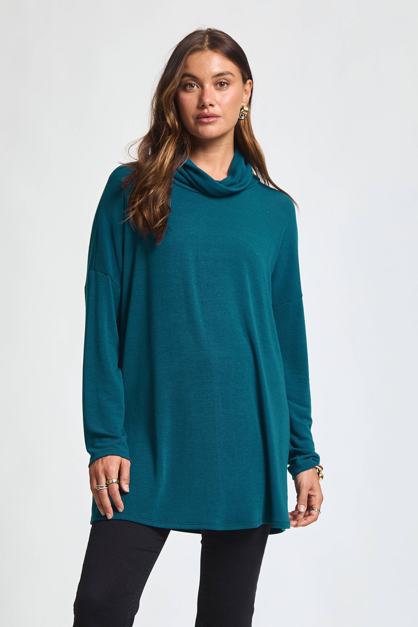 Woman wearing a dark teal open-back cowl neck tunic top with long sleeves from The Pink Doxie Boutique.