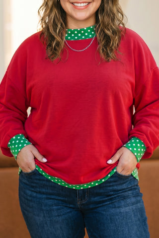 Plus-size red sweatshirt with green polka dot trim on neckline and cuffs.