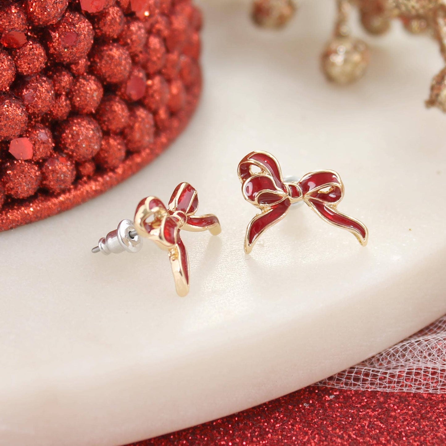 Gold-tone stud earrings with red enamel bow design — festive holiday jewelry from The Pink Doxie.