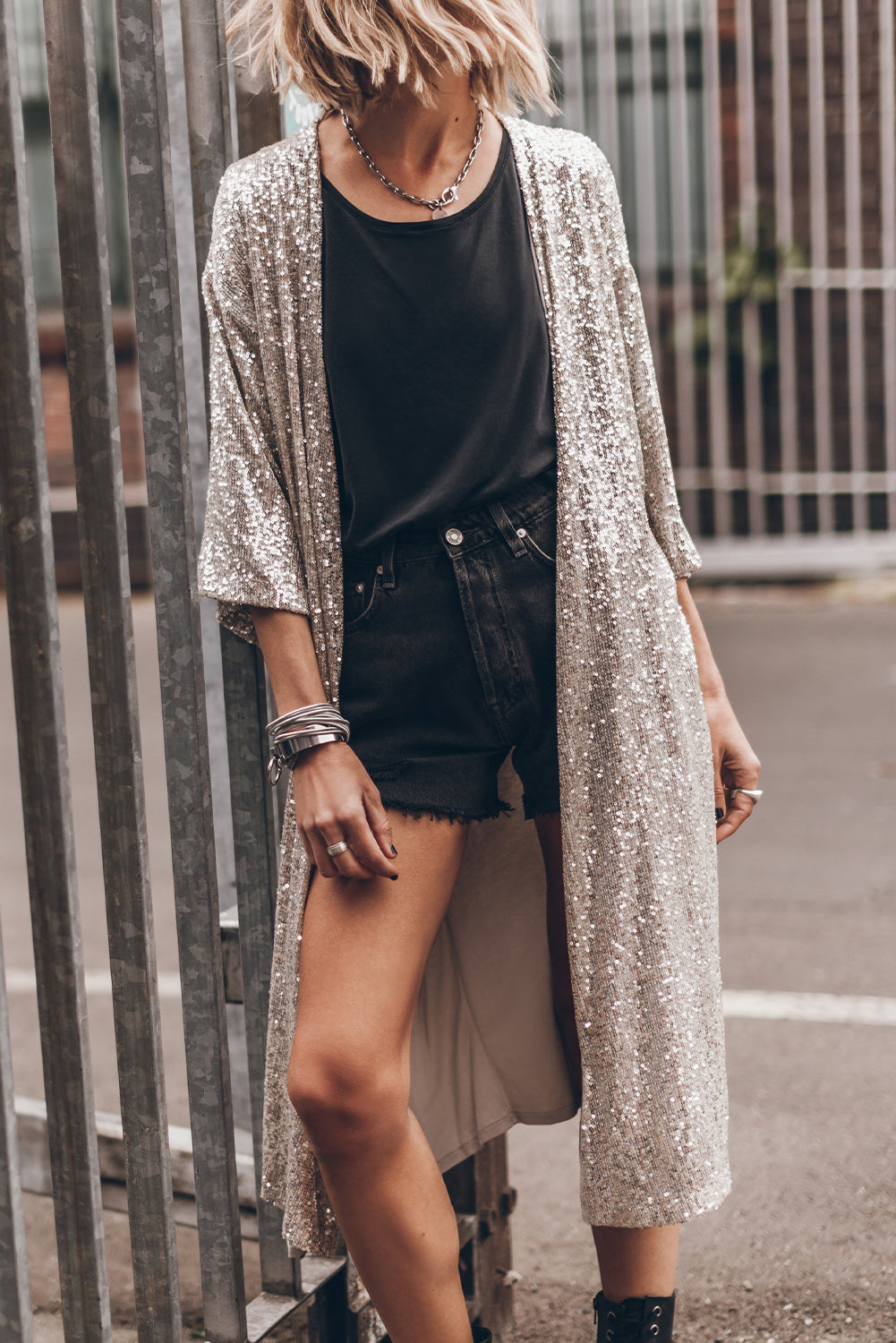 Model wearing sparkly sequin 3/4 sleeve open front duster kimono styled with black shorts and top.