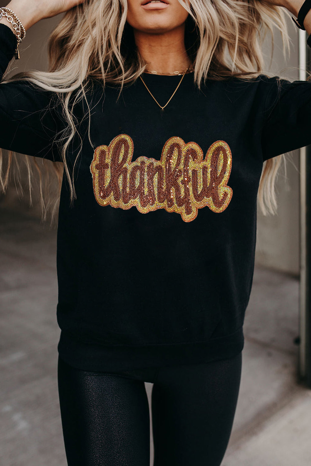 Woman wearing a black “Thankful” graphic sweatshirt with glitter lettering and relaxed fit — fall boutique pullover from The Pink Doxie.