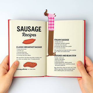 Pink dachshund-shaped bookmark stretching across an open book page.