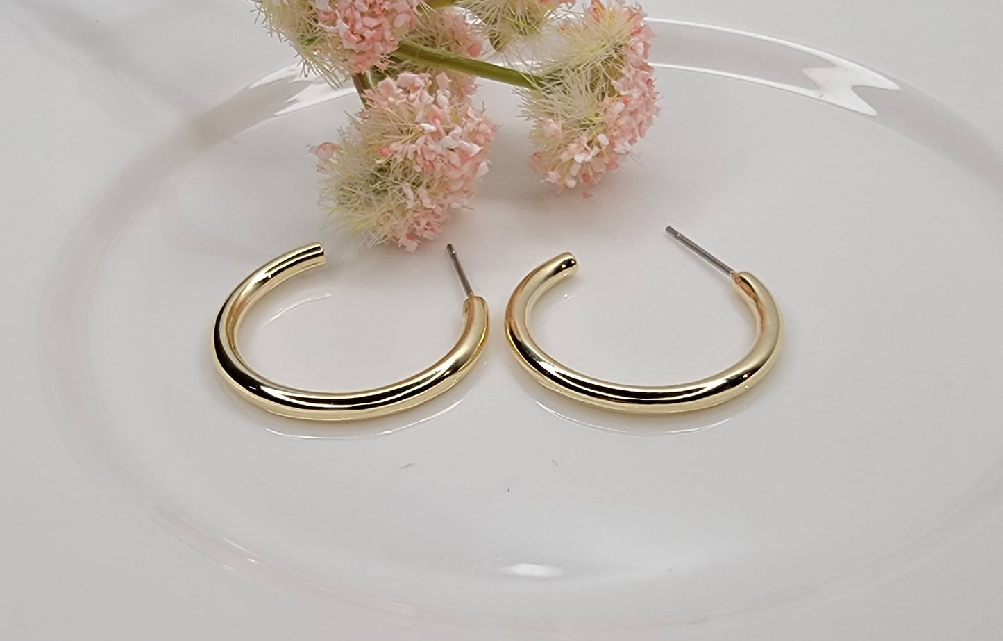 Small gold plated hoop earrings with titanium posts displayed on a white background.