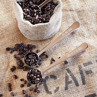 Stainless steel coffee scoop and clip engraved with “Rise and Grind” — one-tablespoon coffee accessory from The Pink Doxie Boutique.