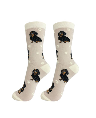 Pair of socks with black dachshund design on a neutral background with paw prints.