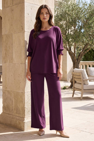A woman wearing a 2-piece set with an oversized poncho top and relaxed-fit pants in a solid color.