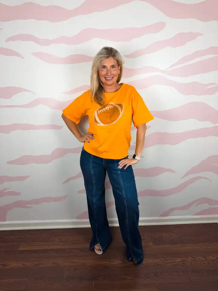 Woman in orange football t-shirt and jeans.
