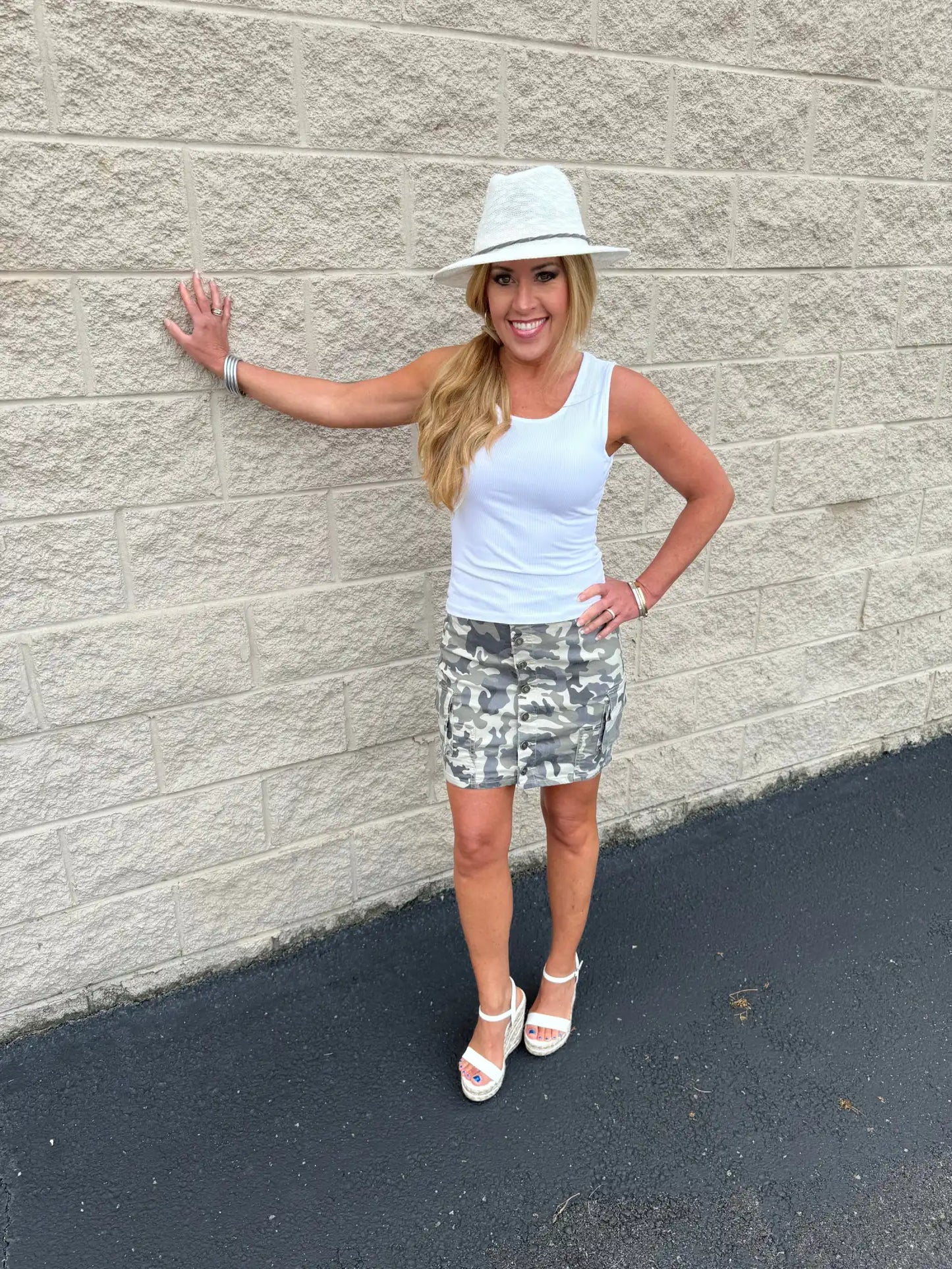 Woman in white tank top and camouflage skirt.